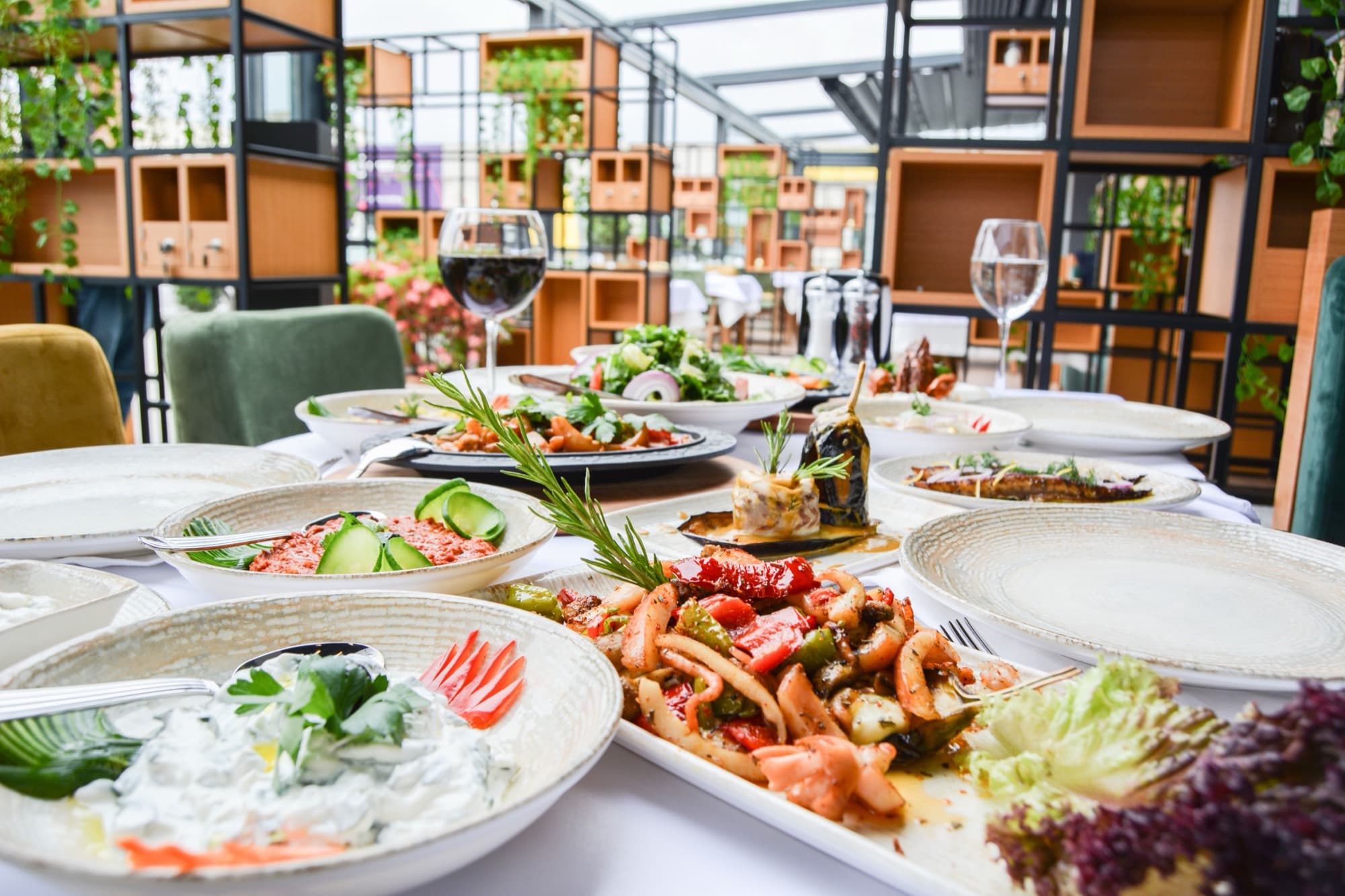 A restaurant terrace table laid with shared dishes and wine